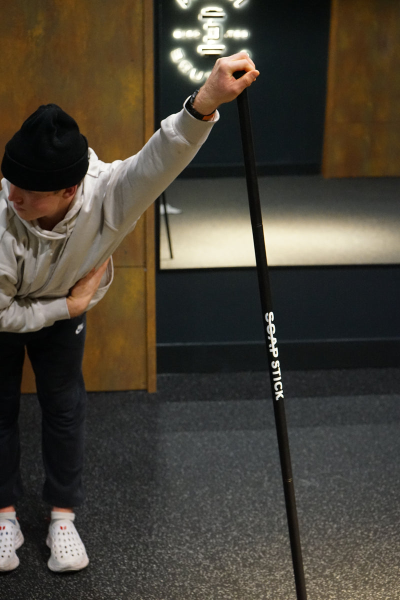 Athlete using ScapStick V2 for overhead shoulder stretch and muscle recovery - buy SCAP Athletics tool